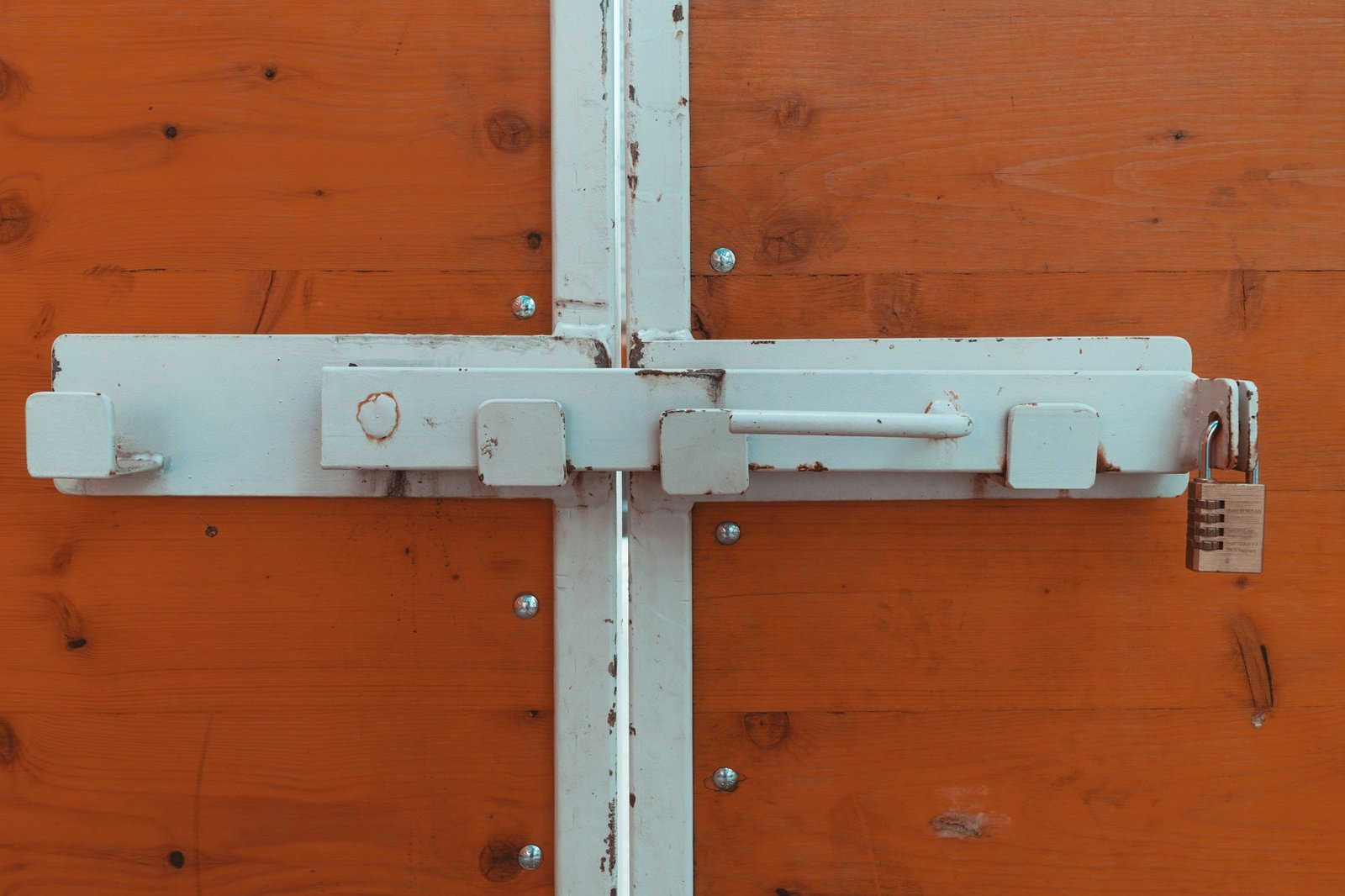 White sliding bolt and combination padlock on timber doors