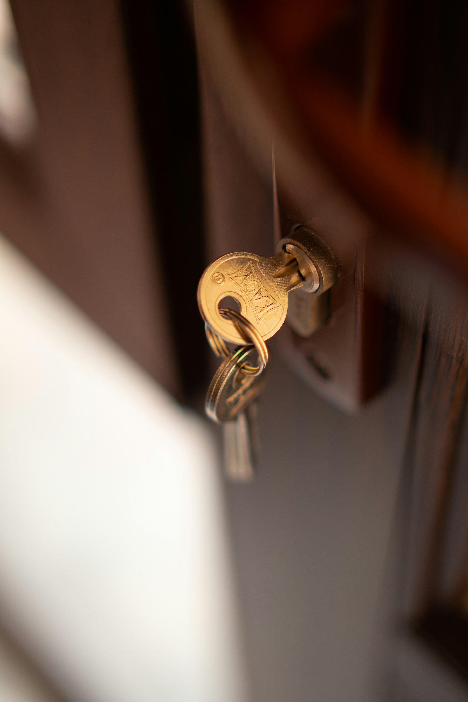 Brass house key in a dark timber door lock